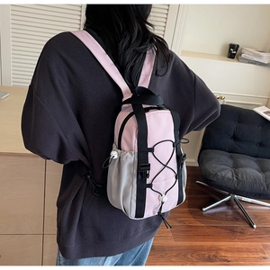 Detail view of mini pink and grey backpack featuring front bungee cord and mesh side pocket