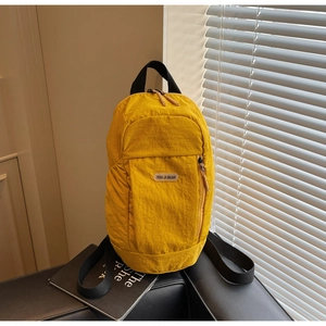 Detail of yellow nylon backpack featuring YOU JI BEAR logo and wide black shoulder strap