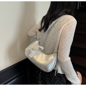 Detail of silver metallic hobo bag with pearl bow charm and pleated texture