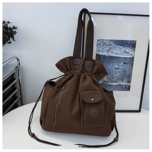 Detail of dark brown drawstring bucket bag with vertical zipper and snap pocket