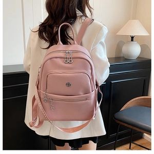 Pink leather backpack detail with stylish metal rings and braided side strap on white blazer