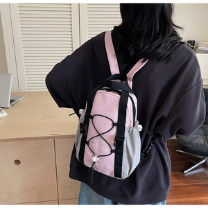 Detail of mini pink and grey backpack featuring front bungee cord and mesh side pocket