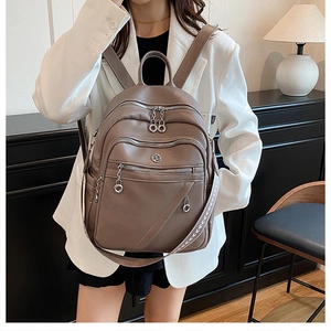 Vista dettagliata dello zaino in pelle marrone con tracolla intrecciata e zip metalliche