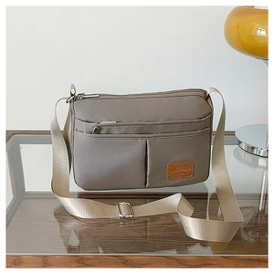 Waterproof nylon shoulder bag detail showing front zipper pockets and khaki finish