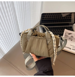 Detail of olive green nylon bucket bag with drawstring closure and webbed shoulder strap