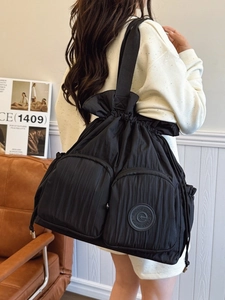 Large black nylon shoulder bag with pleated texture and drawstring closure in casual setting