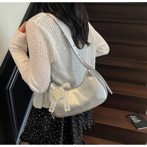 Detail of silver crescent hobo bag with wrinkled texture and pearl heart charm accessory