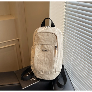 Detail of cream nylon backpack featuring vertical zipper pocket and YOU JI BEAR logo