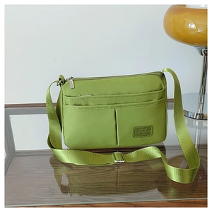 Detailed side view of water-resistant green nylon crossbody bag with multiple zippers