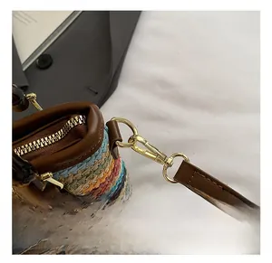 Detail of colorful woven beach bag with golden hardware and brown leather strap