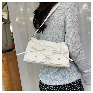 Detail of cream white PU shoulder bag with ribbon bows and dual front pockets