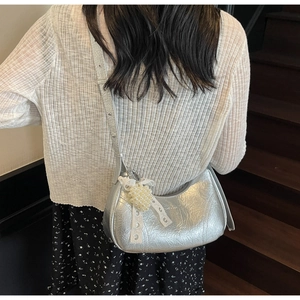 Close-up of silver pleated hobo bag with pearl lace charm and rivet shoulder strap
