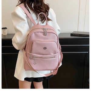 Pink pebbled leather backpack detail with zipper pockets shown on model in street style