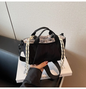 Detail of black canvas bucket bag with drawstring closure and brand logo imprint