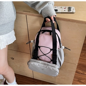 Detailed close-up of a pink and grey nylon backpack with buckle and logo on wooden table