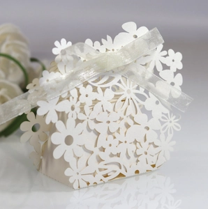 Close-up of laser-cut floral wedding favor box in pearl white with silk ribbon