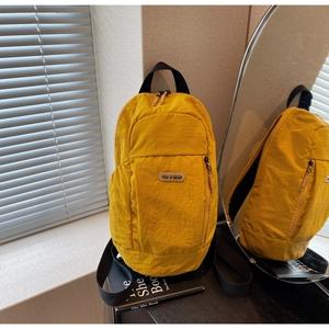 Detail of yellow nylon backpack featuring YOU JI BEAR logo and front zipper pocket