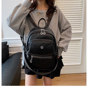 Detail view of stylish black leather backpack with silver zippers on female model