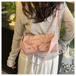 Detail view of pink crossbody bag featuring decorative bows and ruffled texture finish