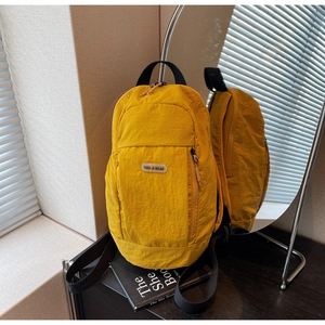 Detail of yellow nylon backpack featuring YOU JI BEAR patch and side zipper pocket