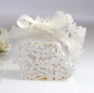 Close-up of laser-cut flower patterns and white satin ribbon on wedding favor box