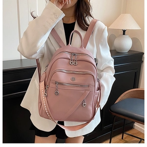 Zaino in pelle rosa indossato da una modella con tracolla intrecciata aggiuntiva