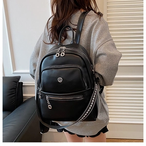 Detailed back view of a black leather backpack featuring silver zippers and woven straps