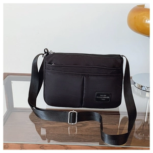 Close-up of black nylon crossbody bag featuring multi-pocket design and brand label