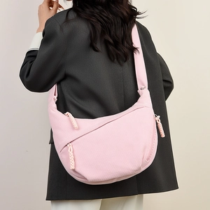 Detailed view of pink corduroy crescent crossbody bag with woven zipper pull details
