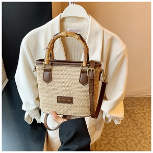 Détail du sac en paille tressée avec poignée en bambou et finitions en cuir marron