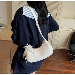 Rear view of a white crescent shoulder bag with pearl cluster and bow details