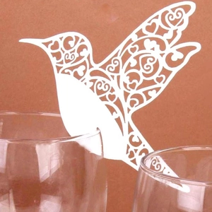 Detailed laser-cut white hummingbird cup cards with heart patterns on glass rims