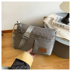 Close-up of gray high-density nylon messenger bag with front pockets and leather patch