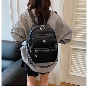 Detail of black leather backpack with multi-zipper compartments and patterned straps