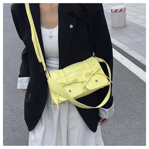 Detail of lemon yellow crossbody bag with decorative bow and functional front pockets