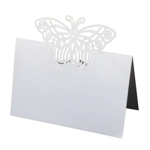 Macro shot of laser-cut pearl white butterfly table card with intricate hollowed details