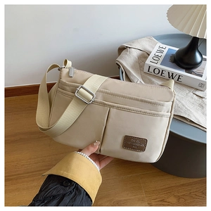 Detail of beige nylon crossbody bag with adjustable wide strap and multi-layer zipper design