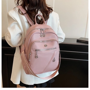 Dettaglio di uno zaino in pelle PU rosa con cerniere argentate e tracolla in tessuto jacquard