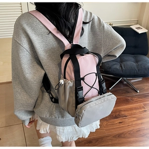 Detail of pink and grey backpack showing adjustable black straps and buckle closure