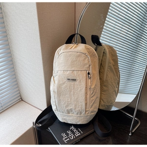 Detail view of beige nylon backpack showing wrinkled texture and brand label
