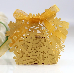 Macro detail of laser-cut floral candy box in gold cardstock with ribbon bow