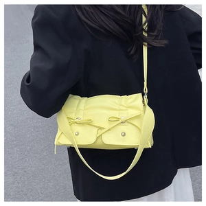Detail of bright yellow leather crossbody bag with bow drawstring and silver metal buckles