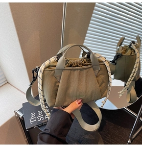 Detail view of olive green drawstring nylon bucket bag with woven handle and wide strap