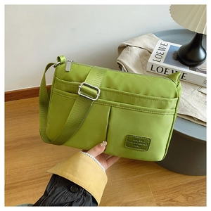 Detail view of the green nylon crossbody bag with side pockets and adjustable strap