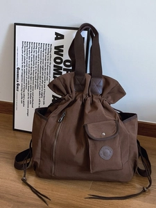 Brown canvas bucket bag with drawstring closure and stylish front pocket detail