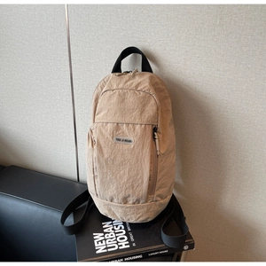 Detail of khaki nylon backpack with brand logo on a modern black leather chair