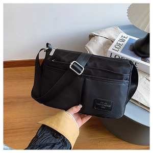Detail of black nylon crossbody bag with multiple zipper compartments and wide strap