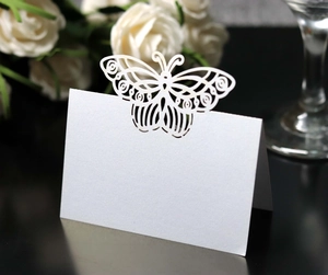 Detail of laser-cut butterfly wedding place card on elegant white pearlescent paper