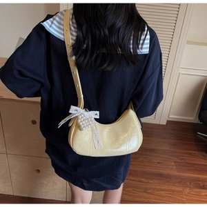 Detail showing pale yellow pleated shoulder bag with pearl heart and lace bow charm