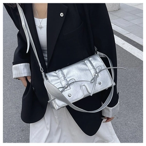 Detail of silver metallic handbag featuring bow ties and textured wrinkled surface
